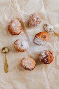 Kaboompics - Overhead Flat Lay of Polish Paczki, Powdered Sugar and Gold Sifter on Cream Fabric