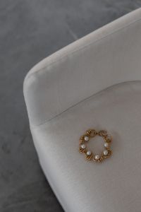 Kaboompics - Pearl and Gold Link Bracelet Styled on a Curved Chair Arm in a Minimal Interior