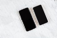 Kaboompics - Two Smartphones with Blank Black Screens on White Marble, Horizontal Background