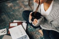 Kaboompics - Woman reading magazines on the floor while enjoying hercup of tea