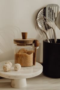 Kaboompics - Brown Sugar Jar with White Coconut Truffles and Kitchen Utensils, Marble Stand Still Life
