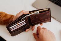 Kaboompics - Brown Leather Wallet Held Over White Desk