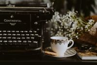 Kaboompics - Vintage Typewriter and Ornate Coffee Cup with Whipped Cream, Mint, Cookie and Flowers