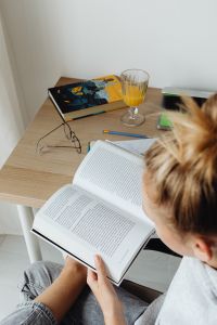 Kaboompics - Open Textbooks, Reading Glasses and Orange Juice on a Study Desk