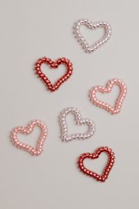 Kaboompics - Six Red, Pink and Pearl Beaded Hearts Scattered on Beige Background, Valentine Flat Lay