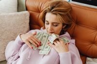 Kaboompics - Woman Holding Dollar Bills Against Her Chest on Sofa
