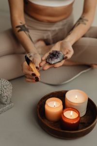Kaboompics - Seated Woman Holding a Crystal and Smoldering Sage Beside Candles