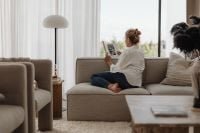 Kaboompics - Woman Reading on a Neutral Sofa in a Sunlit Living Room