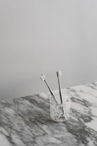 Kaboompics - Two Toothbrushes in Patterned Glass on Marble Counter, Vertical Bathroom Still Life