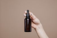 Kaboompics - Close-Up of Hand Cradling Amber Essential Oil Bottle, Neutral Wellness Product Detail