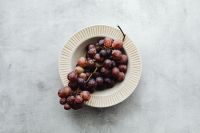 Kaboompics - Overhead Still Life of Grapes in a Fluted Bowl on Pale Stone