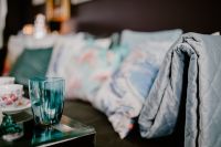 Kaboompics - Blue Drinking Glass on Glass Side Table with Soft-Focus Sofa and Throw
