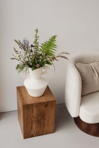 Kaboompics - Minimalist Floral Still Life with White Vase, Wooden Pedestal and Armchair