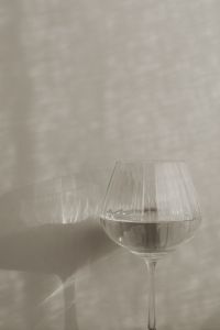 Kaboompics - Water-Filled Ribbed Wine Glass Casting a Shadow on a Beige Wall