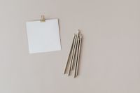 Kaboompics - Paperclip-Held Blank Card with White Pencils on a Beige Studio Surface
