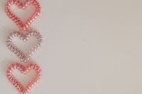 Kaboompics - Three Pink and Pearl Beaded Hearts Along the Left Edge of Beige Background with Copy Space