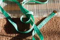 Kaboompics - Green Tape Measure Looped Across Striped and Knitted Fabric for Sewing
