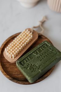 Kaboompics - Wooden Nail Brush and Olive Soap in Close-Up, Natural Hand Care Products on a Round Tray