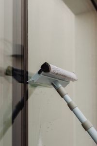 Kaboompics - Woman Cleaning a Glass Window with a Long Squeegee