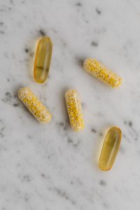 Kaboompics - Golden Softgels and Bead-Filled Capsules on Marble
