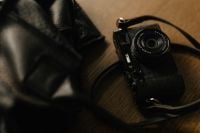 Kaboompics - Black Camera With Leather Strap on Wooden Desk