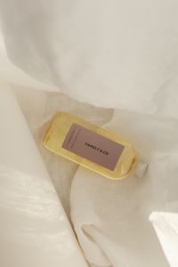 Kaboompics - Amber Fragrance Bottle on Textured White Fabric
