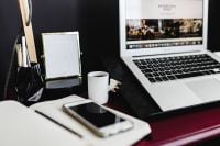 Kaboompics - MacBook and iPhone Beside an Open Notebook on Pink Desk