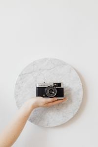 Kaboompics - Vintage Film Camera on an Open Palm Against a Round Marble Background