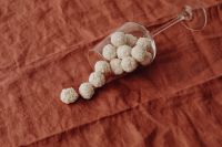 Kaboompics - Coconut-Covered Truffles Spilling from a Glass Goblet onto Rust Linen, Homemade Candy Still Life