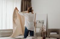 Kaboompics - Woman Pulling Back a Sheer Curtain in the Living Room