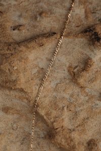Kaboompics - Gold Chain Laid on Pale Porous Malta Limestone