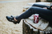 Kaboompics - Seated Woman’s Legs and Red Cola Can on a Beach Stump
