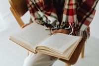 Kaboompics - Woman Reading an Open Book With Plaid Blanket