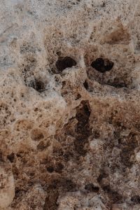 Kaboompics - Porous Beige Coastal Rock with Natural Holes and Loose Pebbles