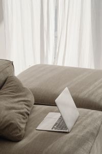 Kaboompics - Open Laptop on Neutral Sofa with Bright Curtain Copy Space, Remote Work Background