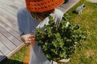 Kaboompics - Overhead Woman Holding a Leafy Plant with Dog in Garden Background