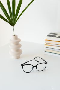 Kaboompics - Eyeglasses and Stacked Books beside a Sculptural Plant Vase