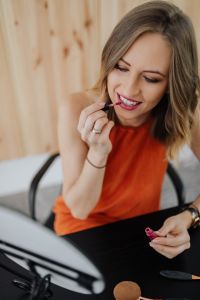 Kaboompics - Smiling Woman Applying Lipstick in a Vertical Beauty Portrait with Copy Space