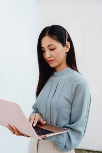 Kaboompics - Thoughtful Asian Woman Working on a Pink Laptop in Close-Up