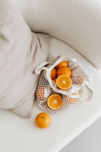 Kaboompics - Mesh Bag of Citrus Styled on an Upholstered Chair beside a Linen Pillow