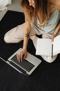 Kaboompics - Woman Typing on a Laptop Beside an Open Planner on the Floor