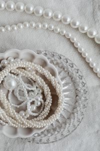 Kaboompics - Pearl Strands Draped Across Linen beside a Scalloped Jewelry Dish on a Glass Tray
