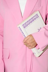 Kaboompics - Person in Pink Suit Holding a White Magazine