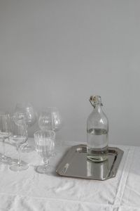 Kaboompics - Glass Bottle and Ribbed Glass on Silver Tray over White Tablecloth