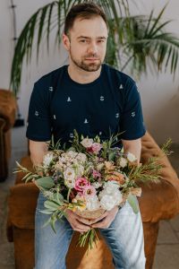 Kaboompics - Man Holding a Large Pastel Bouquet against a Textured Gray Wall