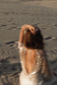Kaboompics - Motion Blur Faceless Woman Sitting on Beach in Sequin Dress