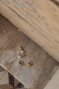 Kaboompics - Gold Rings and Pearl Drop Earrings Scattered on a Neutral Stone Surface, Jewelry Still Life