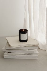 Kaboompics - Lit Black Candle on Stacked Books by Sheer Curtains