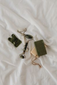 Kaboompics - Green Stone Facial Roller, Gua Sha and Handmade Soap Bars on White Linen