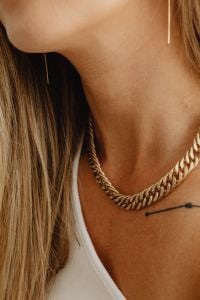 Kaboompics - Gold Chain Necklace and Collarbone Tattoo with a White Ribbed Top, Close-Up